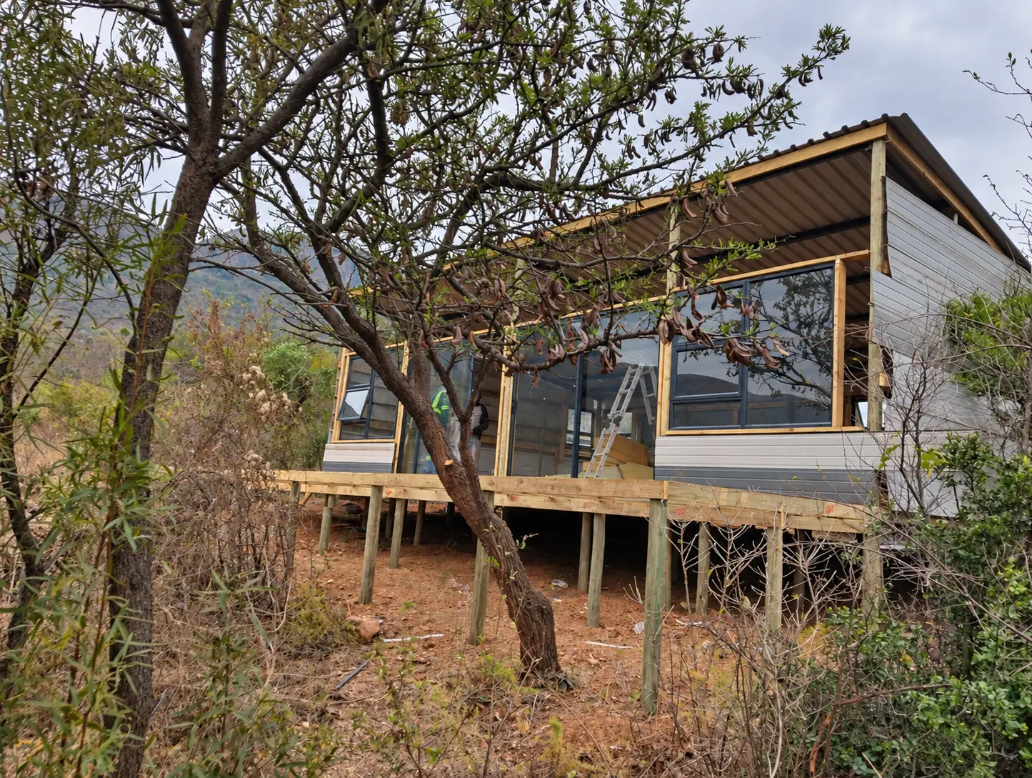 The new Sango Hartbeespoort unit seen through surrounding bush, raised on timber posts against the mountainside